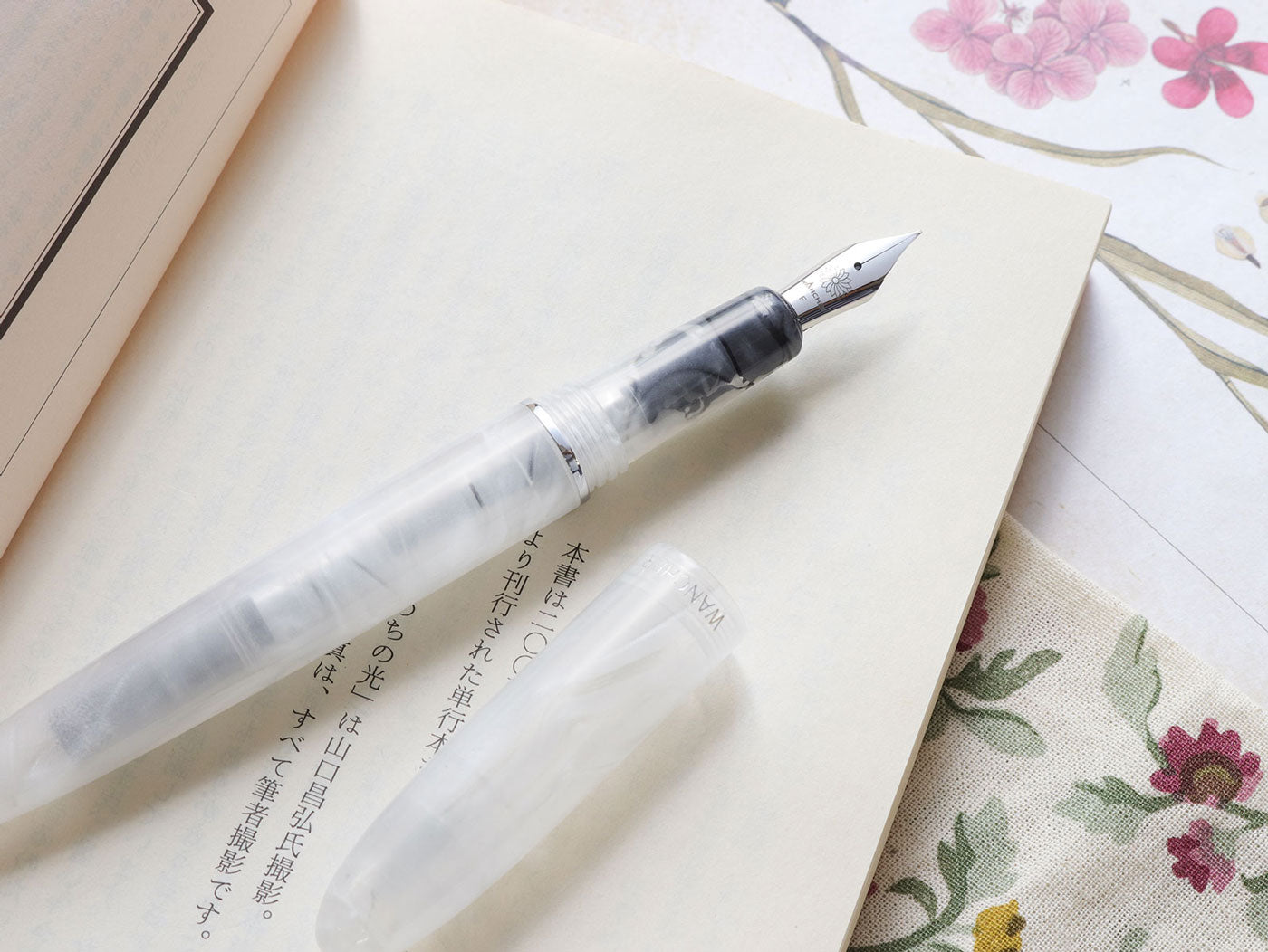 Wancher 1 x one x Wan MOFU Fountain pen on a piece of paper with floral background