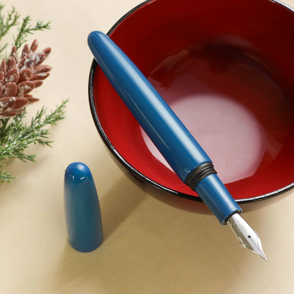 Aizu Urushi Ao fountain pen with a deep blue being uncapped showing a lustruous finish