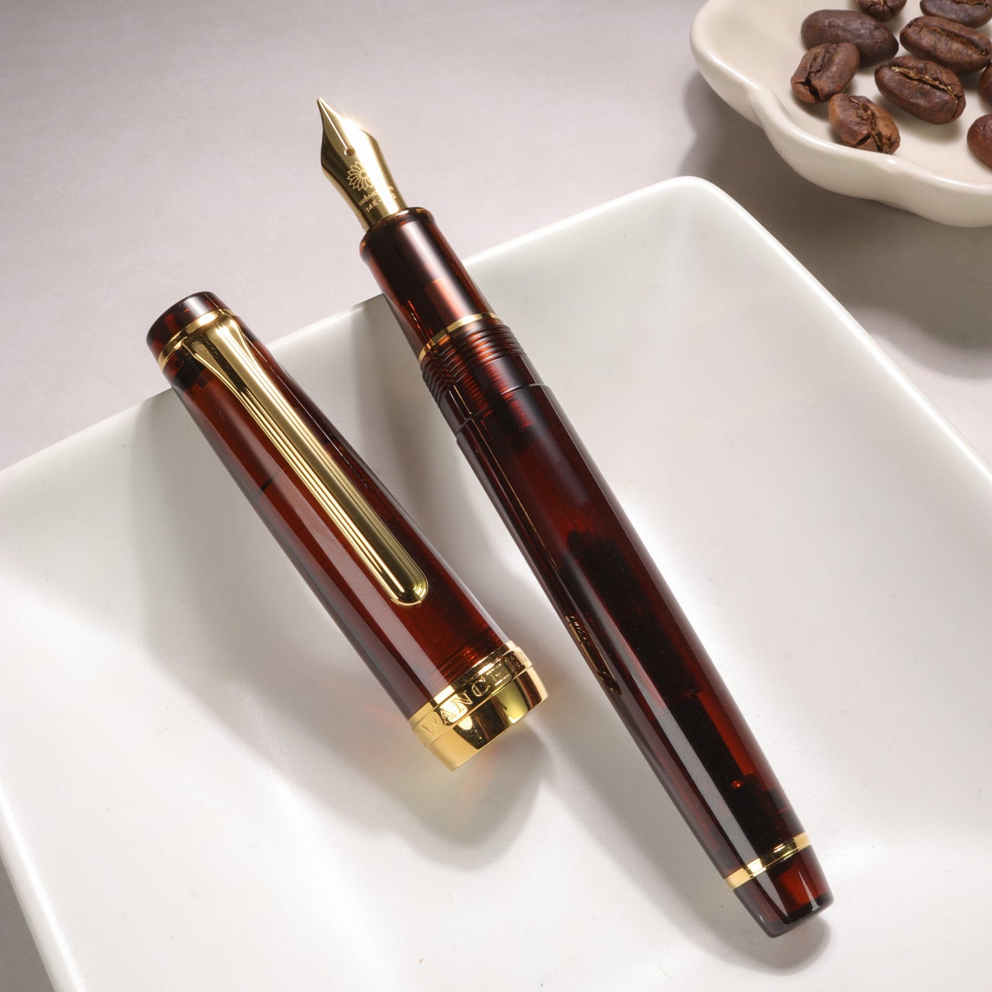 Brown fountain pen with gold accents on a white plate, coffee beans in the background