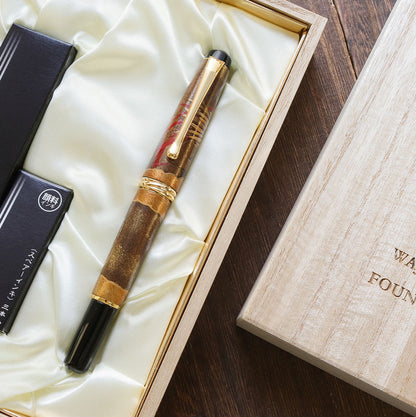 Brush pen with Wajima-nuri Maki-e Dragon hand-drawn in a wooden box on a wooden surface